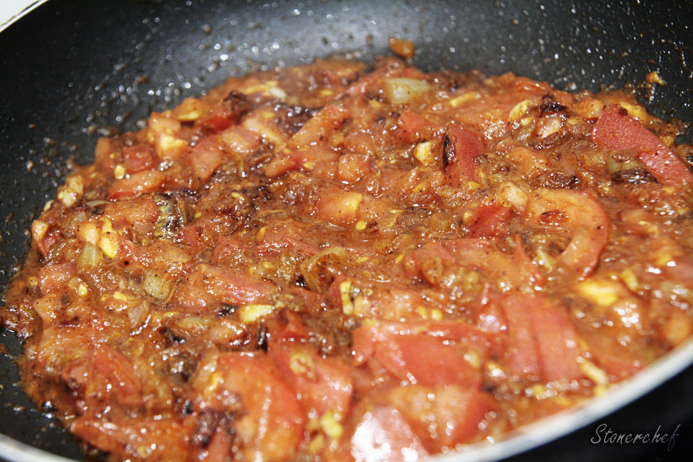 cebula czosnek i pomidory w przyprawach na patelni